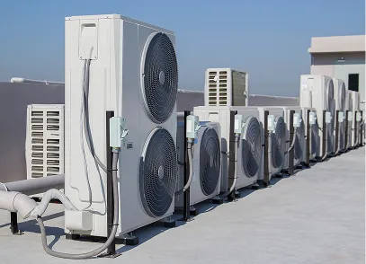Row of outdoor HVAC units with large fans installed on a rooftop under clear blue sky.