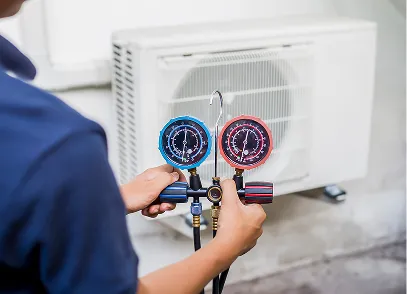 Technician using a manifold gauge set to check the pressure of an outdoor air conditioning unit.