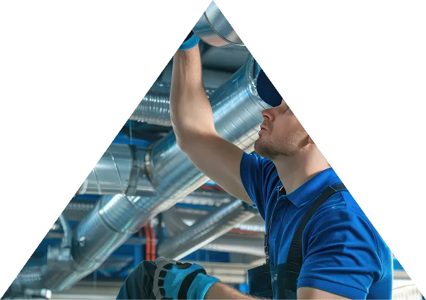 Technician inspecting and working on industrial HVAC ducting inside a commercial building.