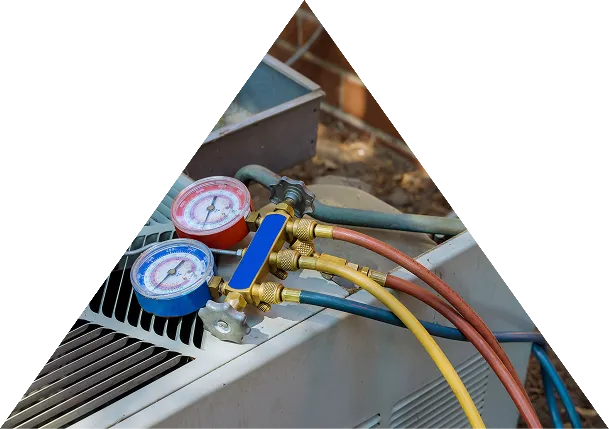 Pressure gauges with blue and red dials connected to hoses on an air conditioning unit.
