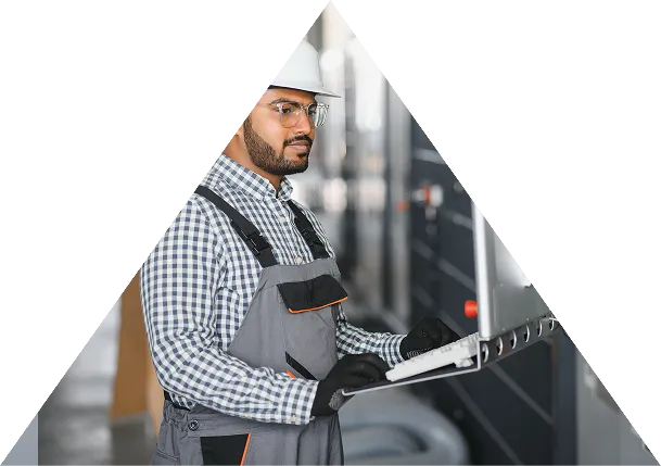 Engineer in safety helmet and gloves operating control panel in an industrial setting.