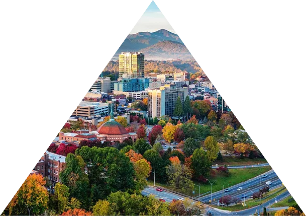 Aerial view of a cityscape with colorful autumn trees, buildings, and a highway with cars, framed in a triangular shape.