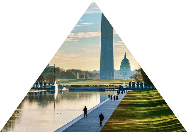 People walking along the National Mall in Washington, D.C., with the Washington Monument and the U.S. Capitol visible in the background.