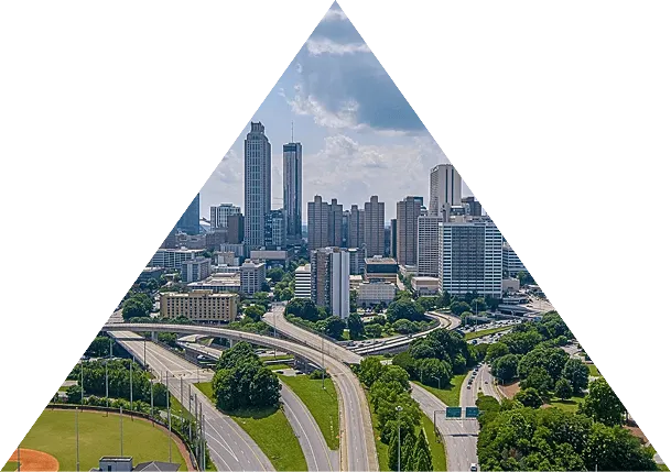 Aerial view of a cityscape with highways, green parks, and skyscrapers under a partly cloudy sky.