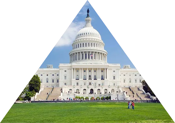 Front view of the United States Capitol building with a green lawn and people in the foreground.