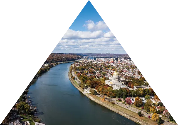 Aerial view of a city along a river with autumn trees and a prominent domed gold-roofed building.