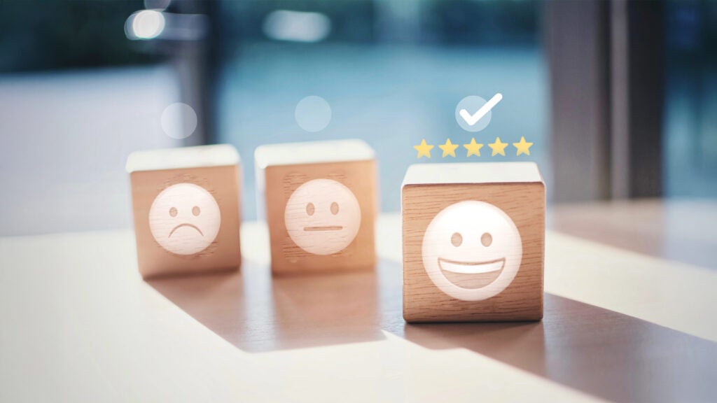 Three wood blocks with a sad, neutral, and happy face emoji on them.