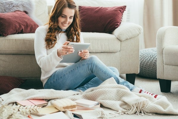 Woman sitting on the floor looking at her tablet.