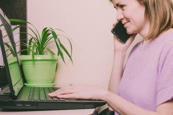 Customer talking on the phone while typing on a computer keyboard.
