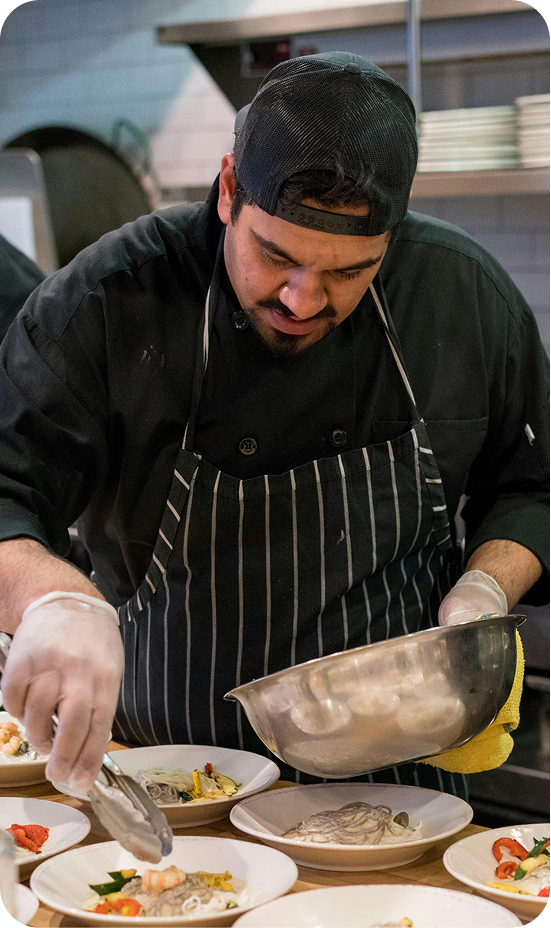 A man in a chef's uniform preparing food on a table.