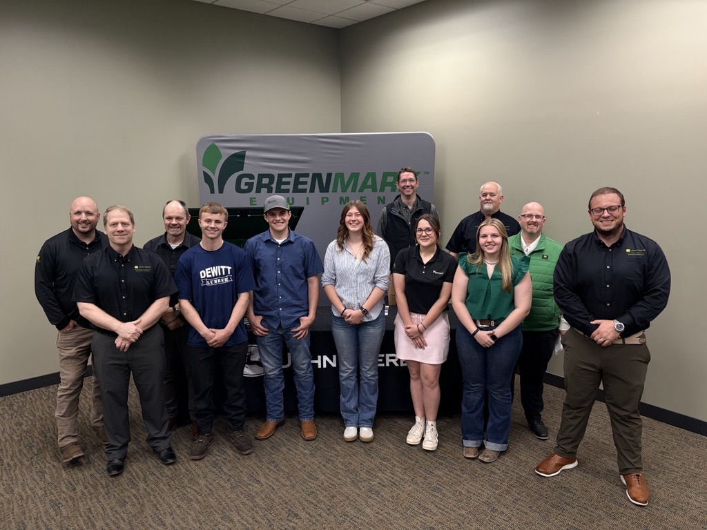 Students stand with employees in front of a GreenMark banner after signing to join the GreenMark Technician Program.