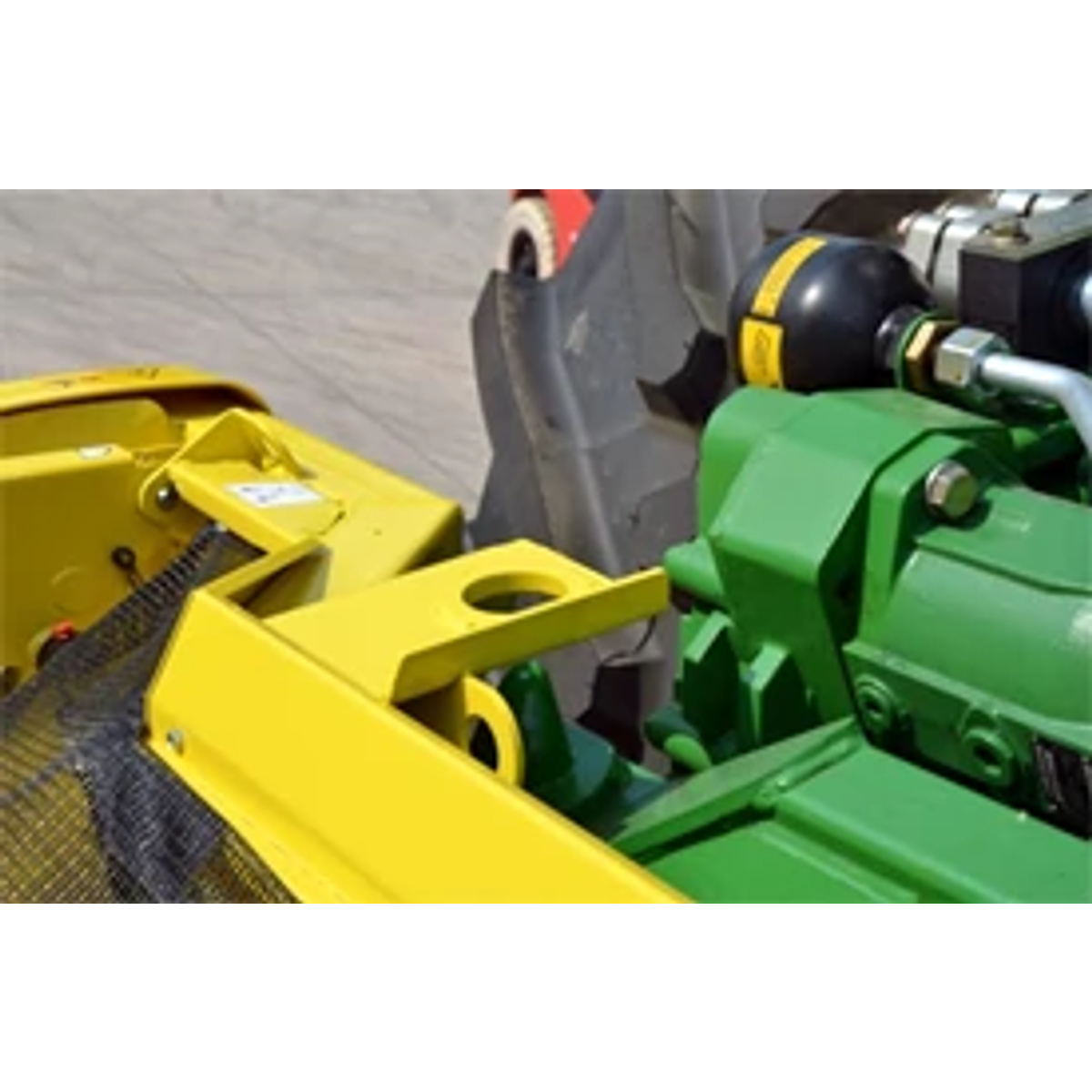 Close-up of yellow and green frame components of a 600 series windrow pick up header's hookup point