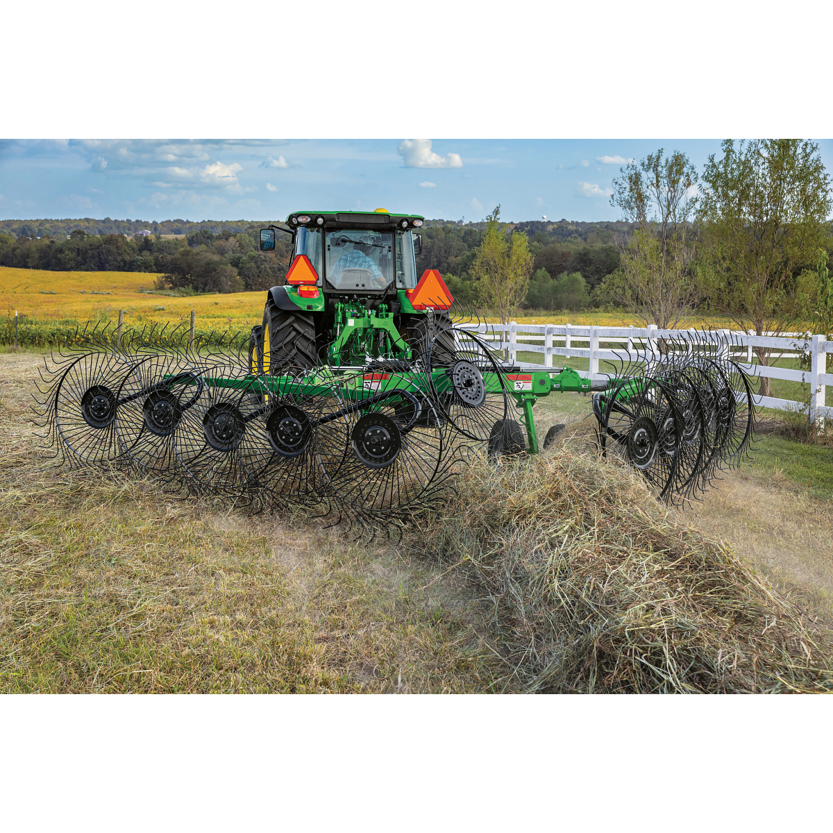 Rear view of a 5M tractor using a WR3210 wheel rake in the country