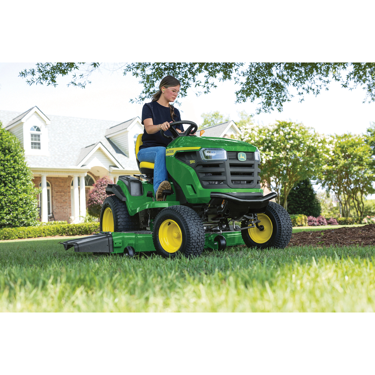 Front right view of a homeowner using an S180 Lawn Tractor on a residential lawn