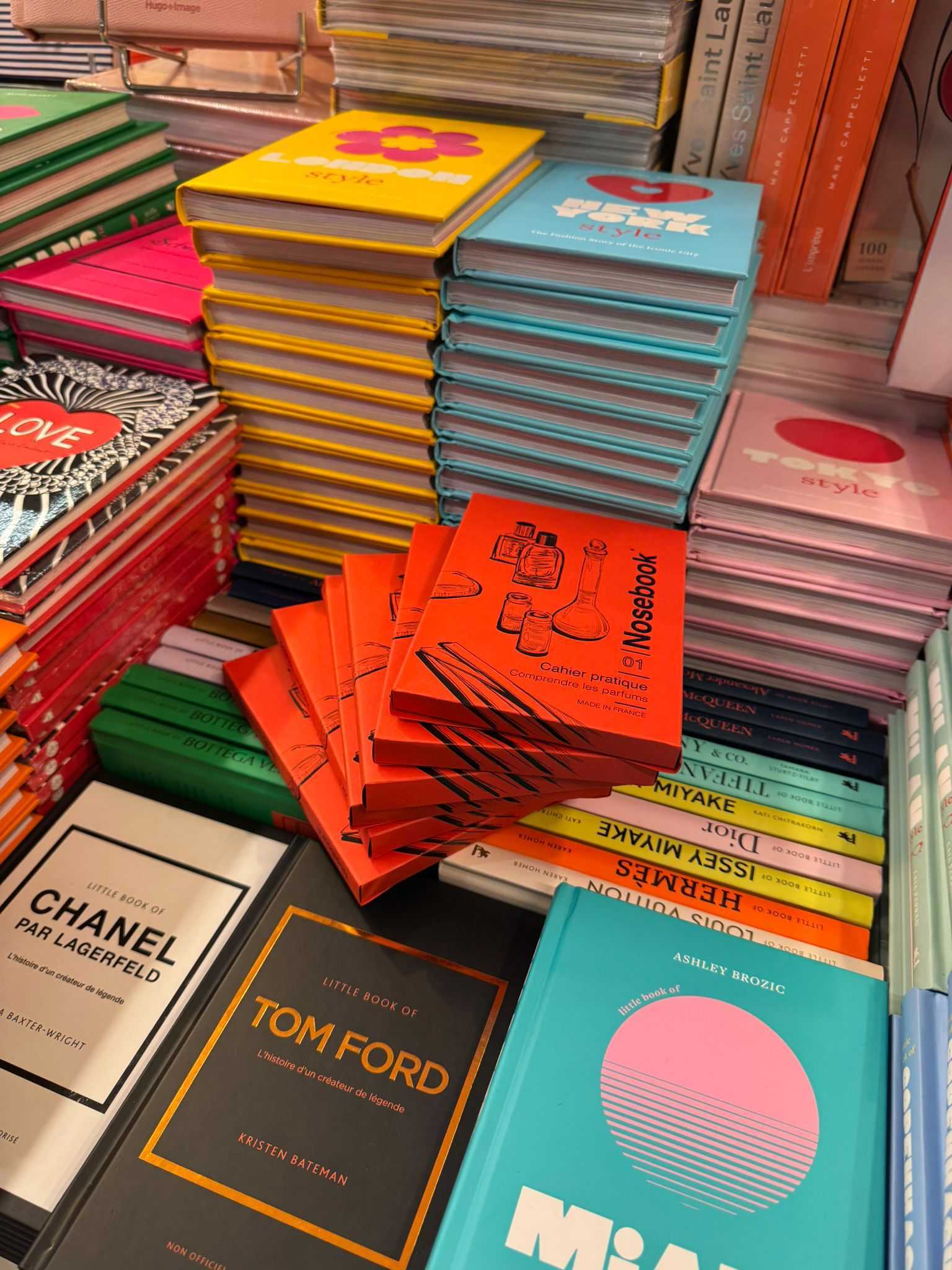 Empilements de livres colorés sur la mode et le style, y compris des titres, au centre de la photo trône des petits guides sur les parfums, les coffrets Nosebook.