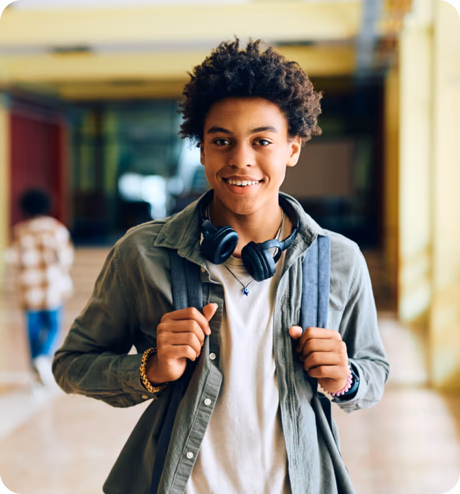 Child smiling with backpack on, holding the handles, following a successful psychoeducational evaluation. 
