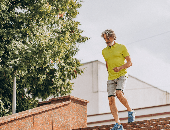 Stariji muškarac hoda niz stepenice nakon ortopedskog oporavka