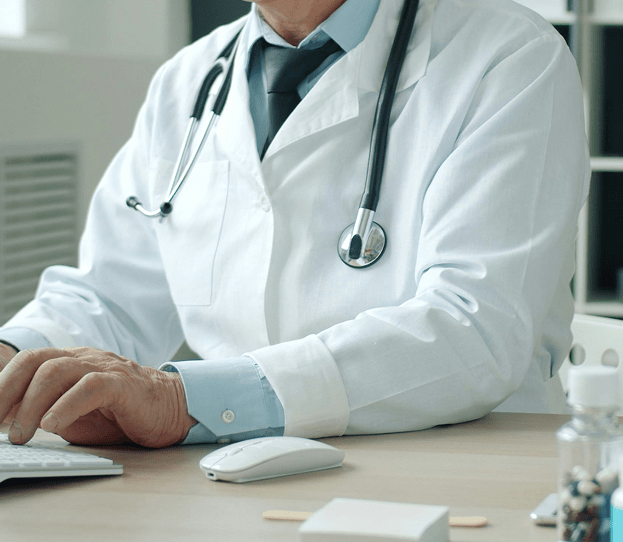 Lekar u belom mantilu radi na računaru u ordinaciji