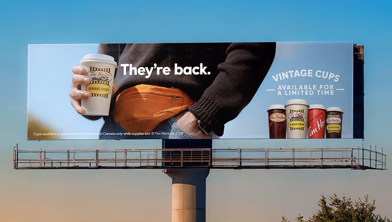 Billboard showing a person holding a Tim Hortons vintage cup with text 'They’re back.' and 'Vintage cups available for a limited time' alongside images of four different vintage Tim Hortons cups.