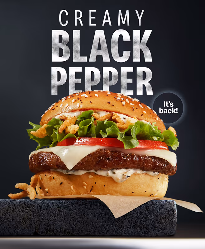 Creamy Black Pepper burger with lettuce, tomato, melted cheese, and crispy onion on a sesame seed bun.