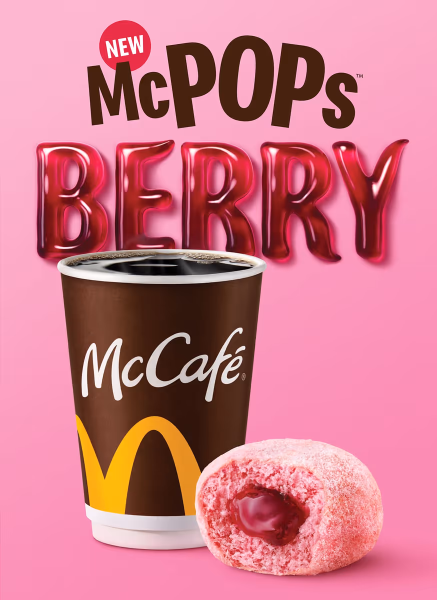 McCafé coffee cup next to a pink McPops Berry donut with berry filling on a pink background.
