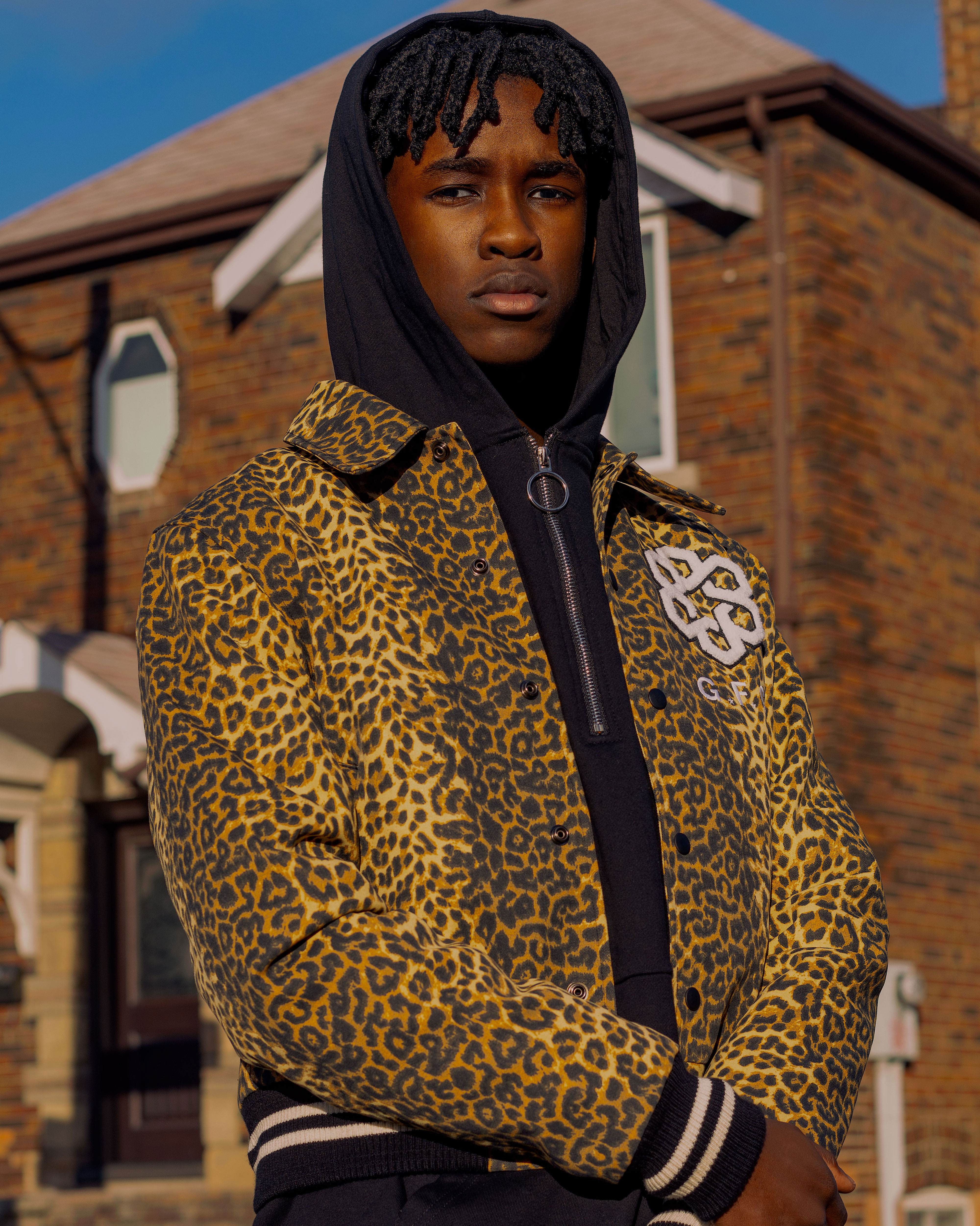 young man in leopard print jacket photographed outdoors in the sun by fashion photographer
