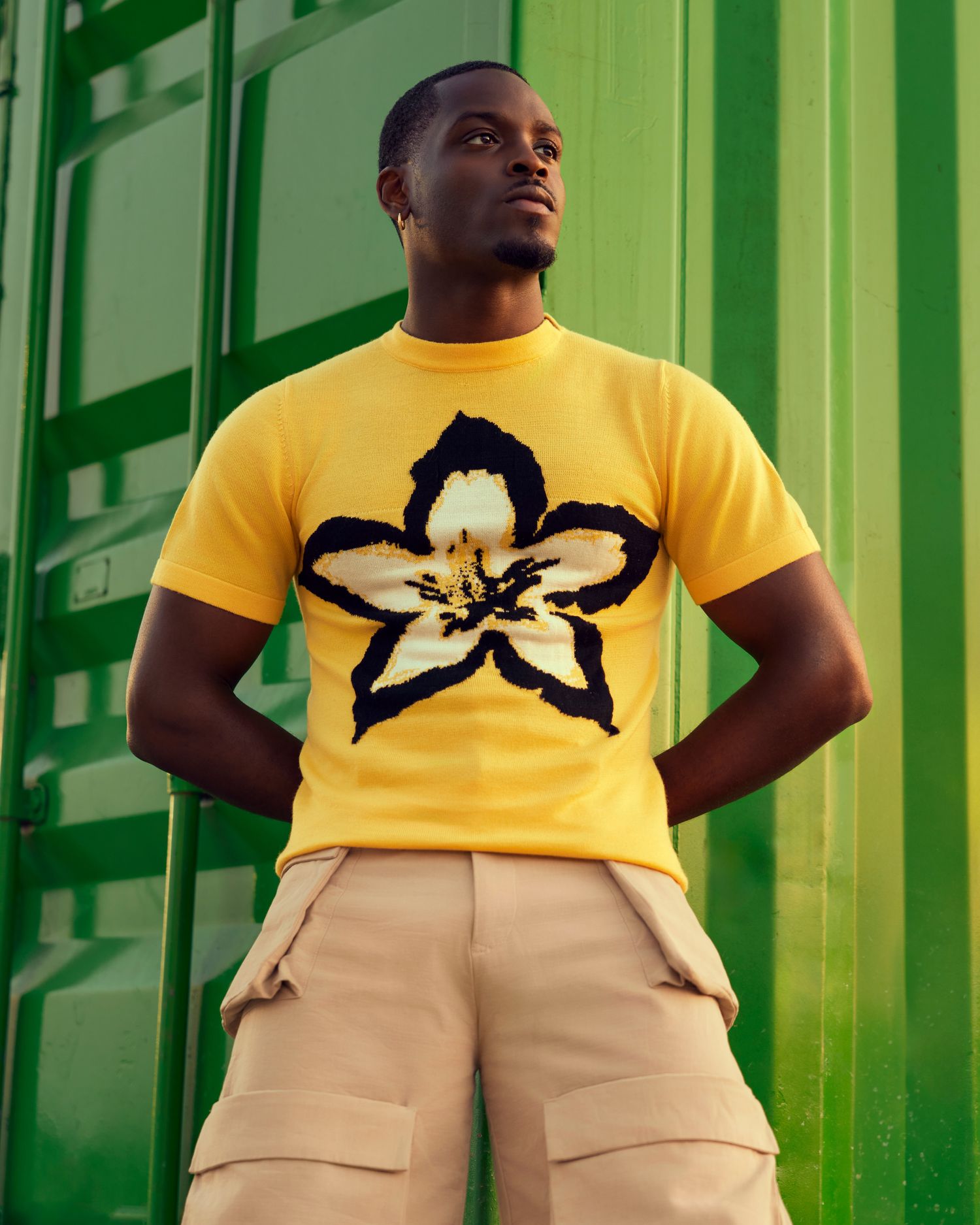 A powerful portrait of a man in front of green shipping containers for a fashion photography shoot. 