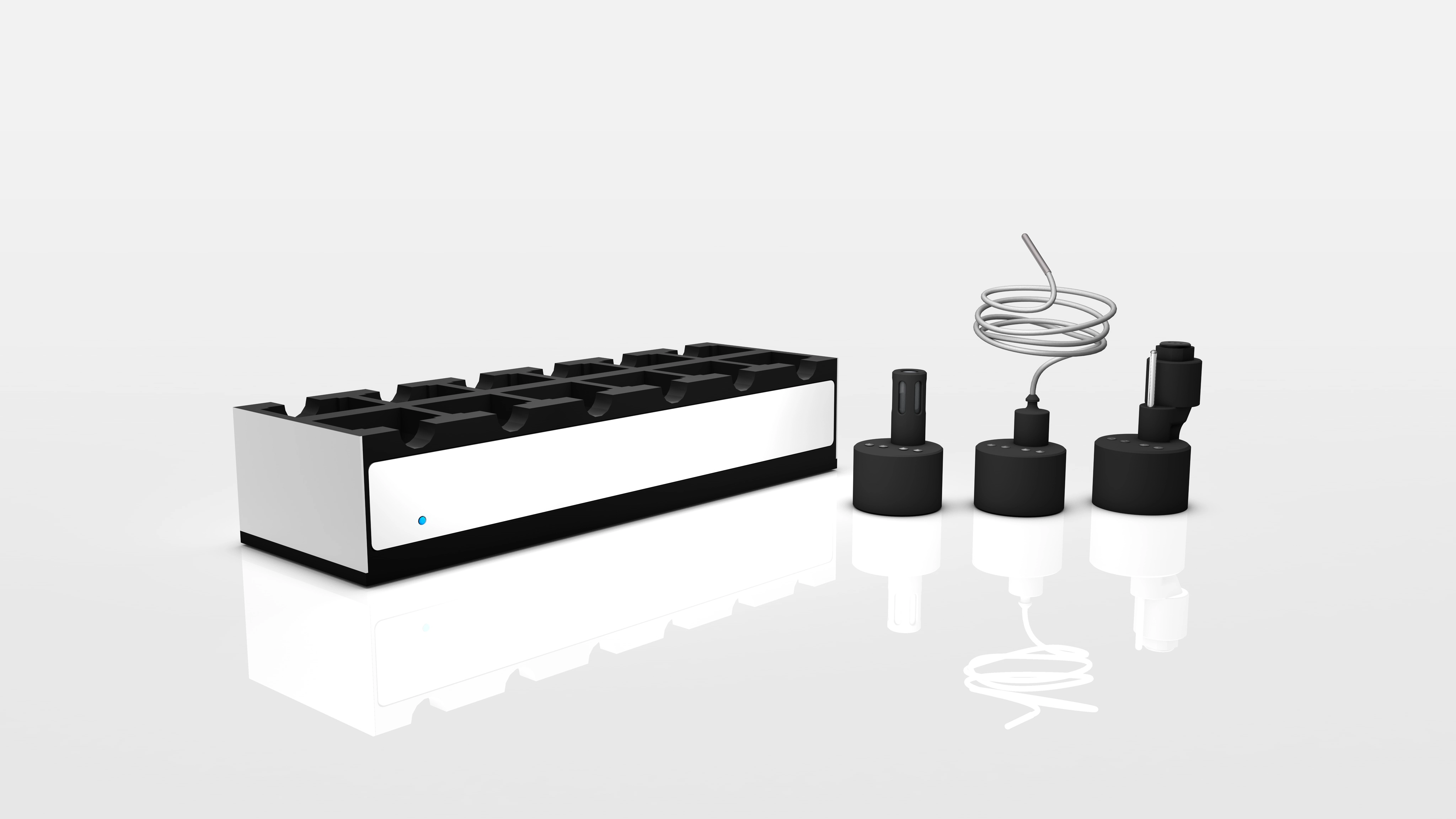 Set of black and silver electronic components including a rectangular holder with multiple slots and three connected cylindrical probes or sensors with wires.