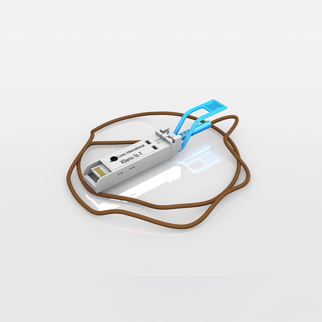 Close-up of a white XSens-TC-T sensor module with a brown cable and a blue clip on a reflective surface.