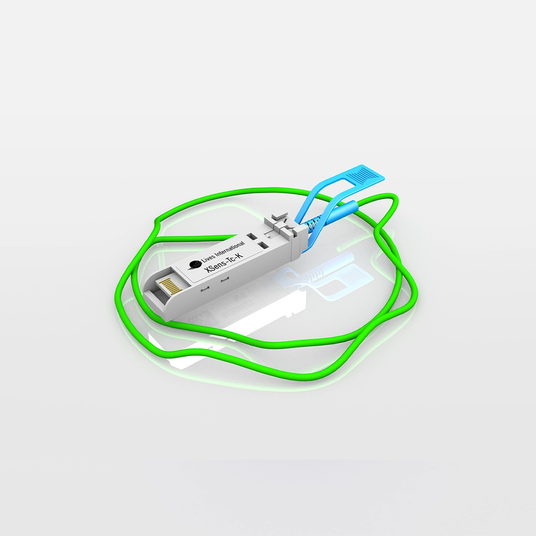 XSens-TC-K sensor device with green cable and blue connectors on a reflective surface.