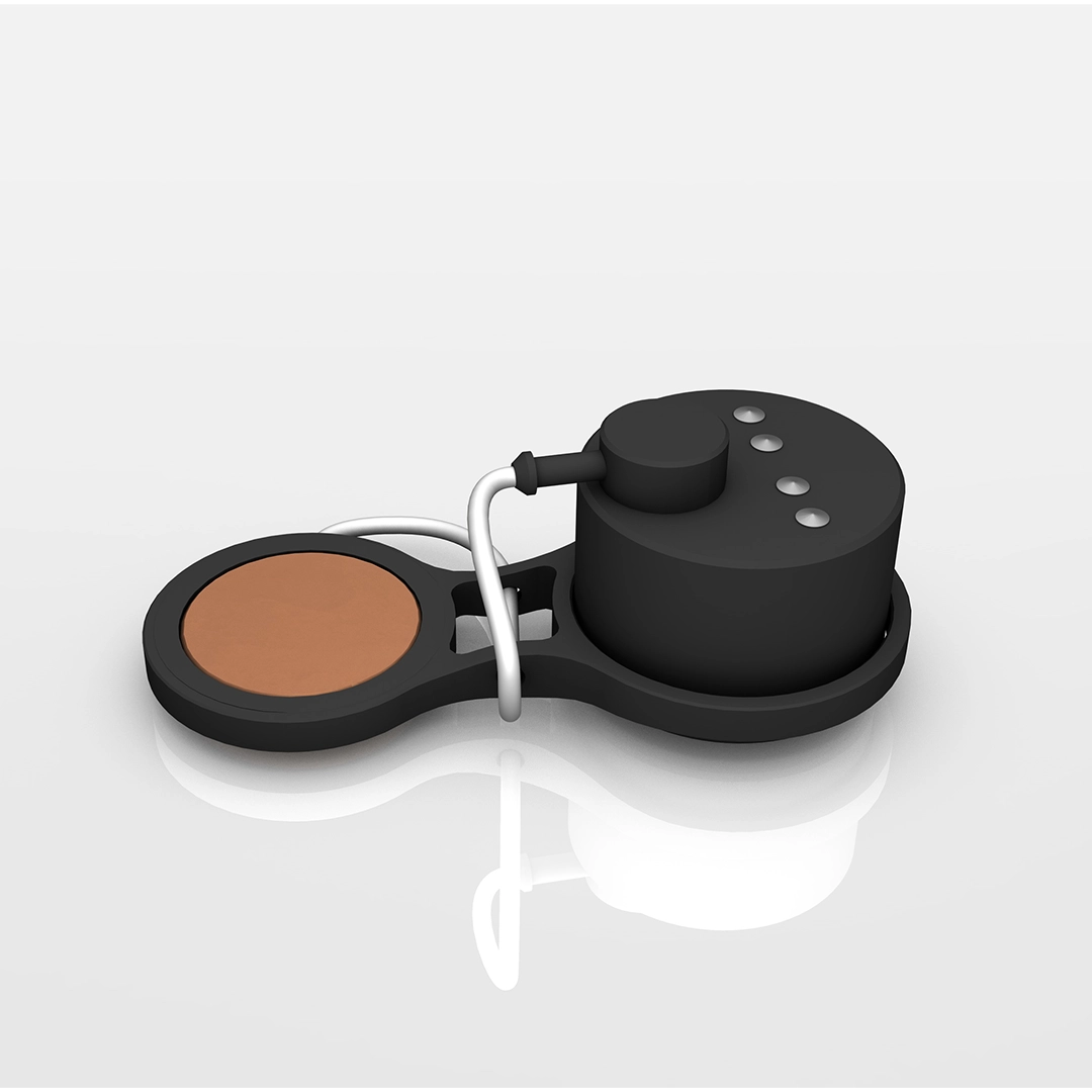 Compact black device with a circular brown pad and attached cable, placed on a reflective white surface.
