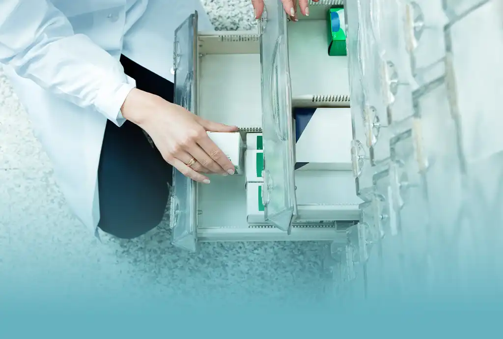 A pharmacist is choosing a vial size from a drawer.