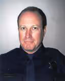 Portrait of a middle-aged man in a dark uniform against a plain background.