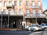 Street view of a historic brick building with a pharmacy storefront and parked cars in front.