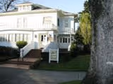 White two-story house with a large tree in the front yard and a pathway leading to the entrance.