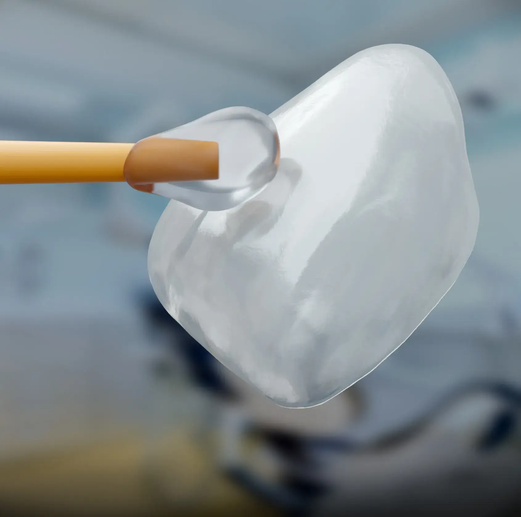 Close-up of a transparent dental veneer held by a tool against a blurred background.