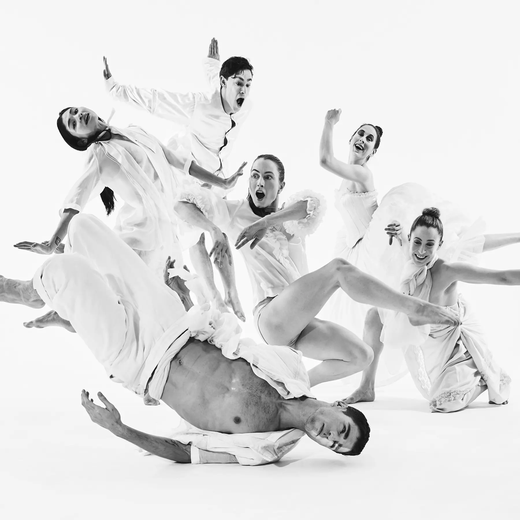 Group of contemporary dancers performing an expressive composition in a minimalist white studio