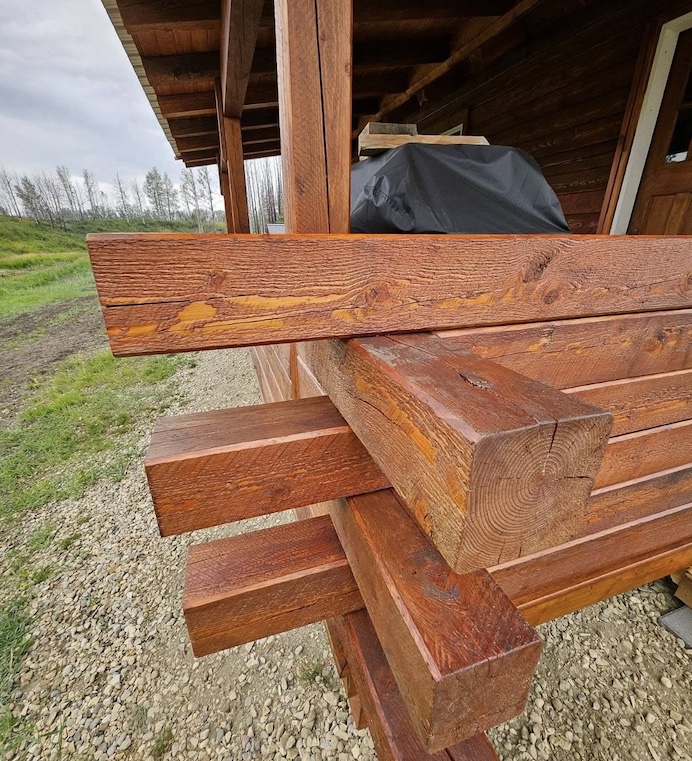 Close-up of interlocking wooden beams on a timber structure, showcasing smooth stained wood and precise joinery.