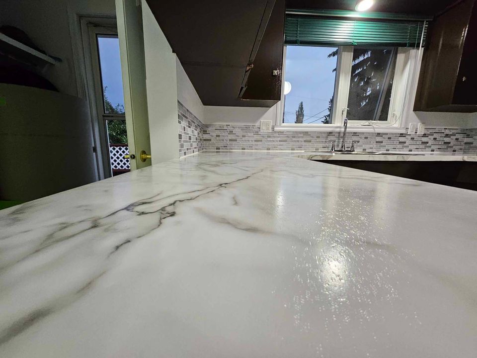 Close-up view of a polished white marble countertop with subtle gray veining in a modern kitchen setting.