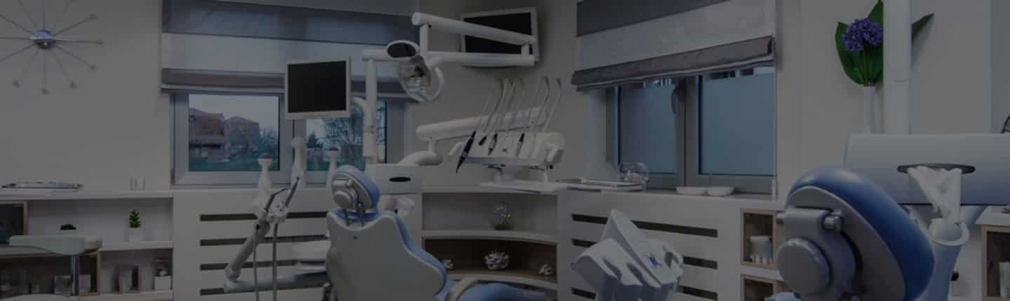 Modern dental office with blue dental chairs, dental equipment, and large windows.