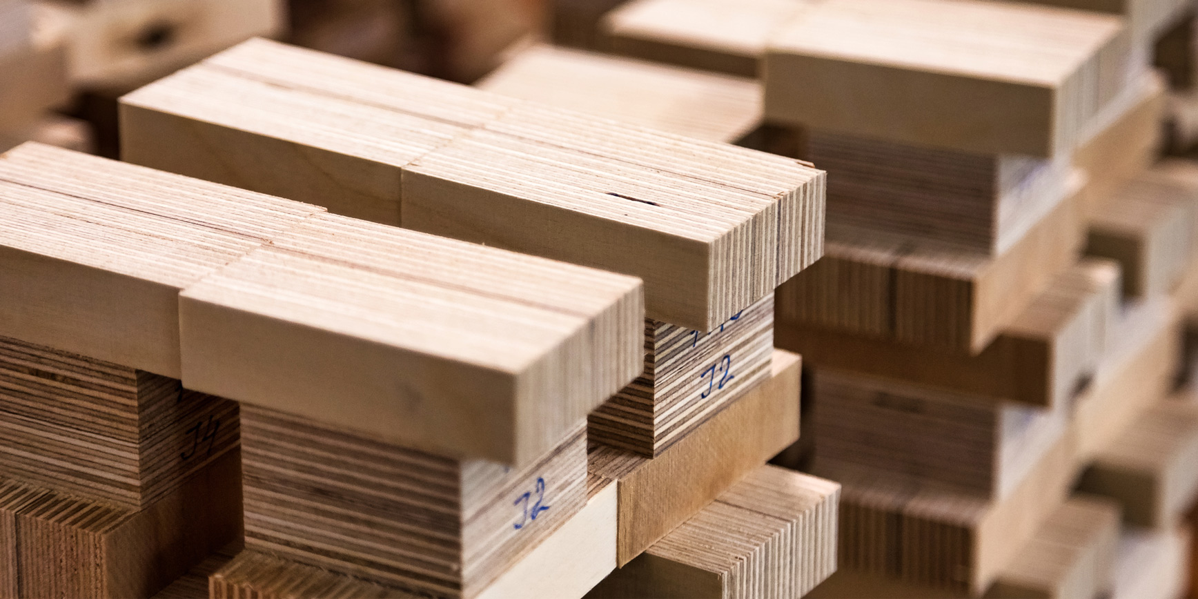 Gestapelte Holzstücke unterschiedlicher Größe mit Beschriftungen auf den Kanten.