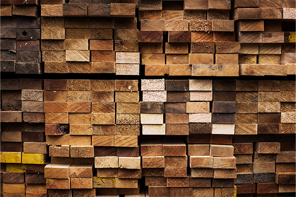 Gestapelte Holzbretter unterschiedlicher Braun- und Beigetöne in einem Holzhandel.