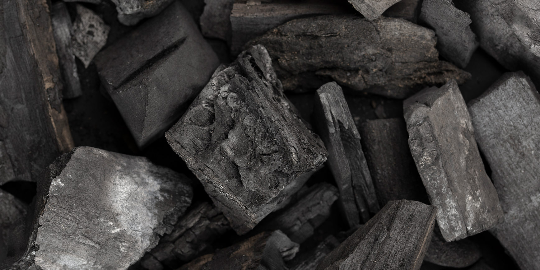 Nahaufnahme von schwarzer Holzkohle mit rauer, unregelmäßiger Oberfläche.