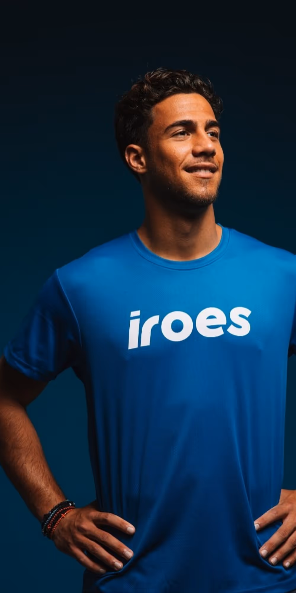Male soccer player in red and white striped uniform running with a soccer ball.