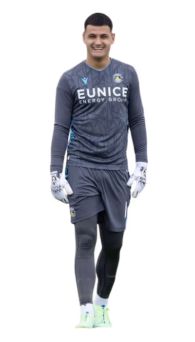 Smiling soccer goalkeeper walking, wearing dark gray uniform with Eunice Energy Group logo, gloves, and light green cleats.