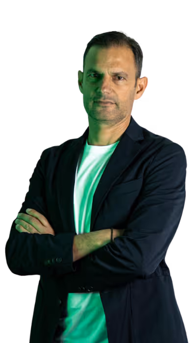 Man with short hair wearing a black blazer and white shirt standing with arms crossed.