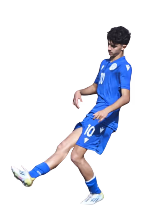 Young male soccer player in blue uniform kicking a ball.