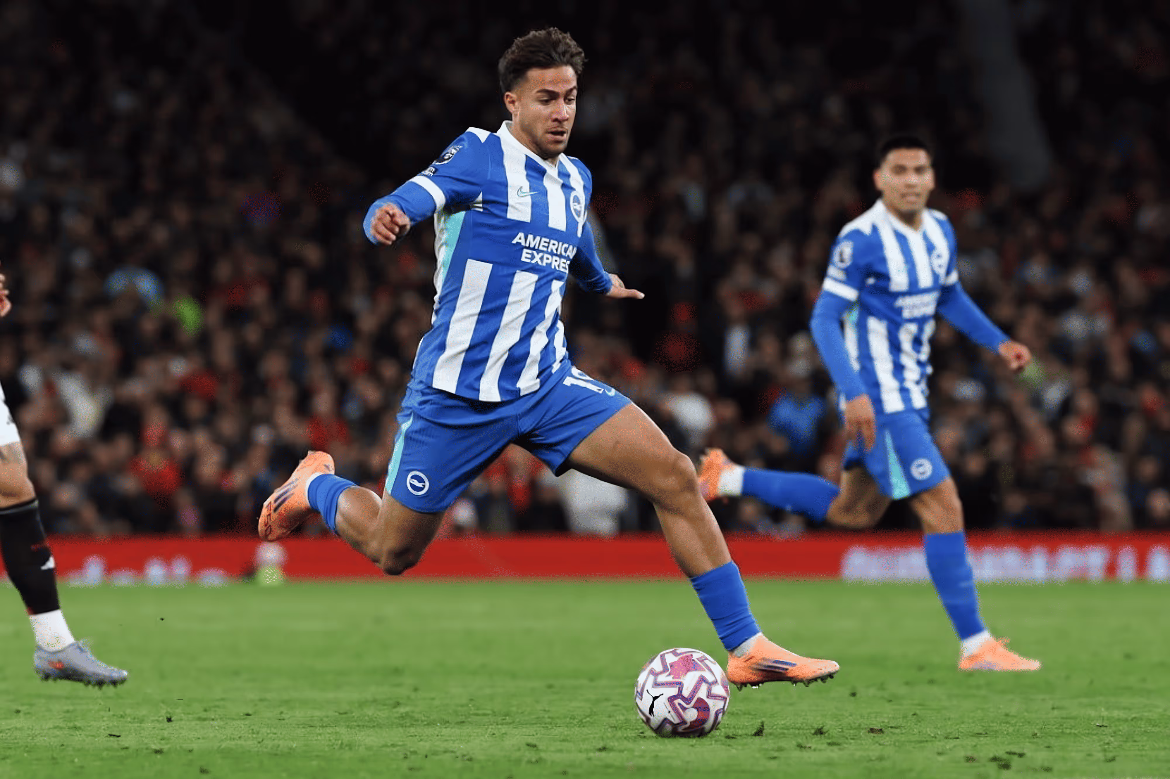 Brighton soccer player in blue and white stripes kicking a soccer ball during a match.