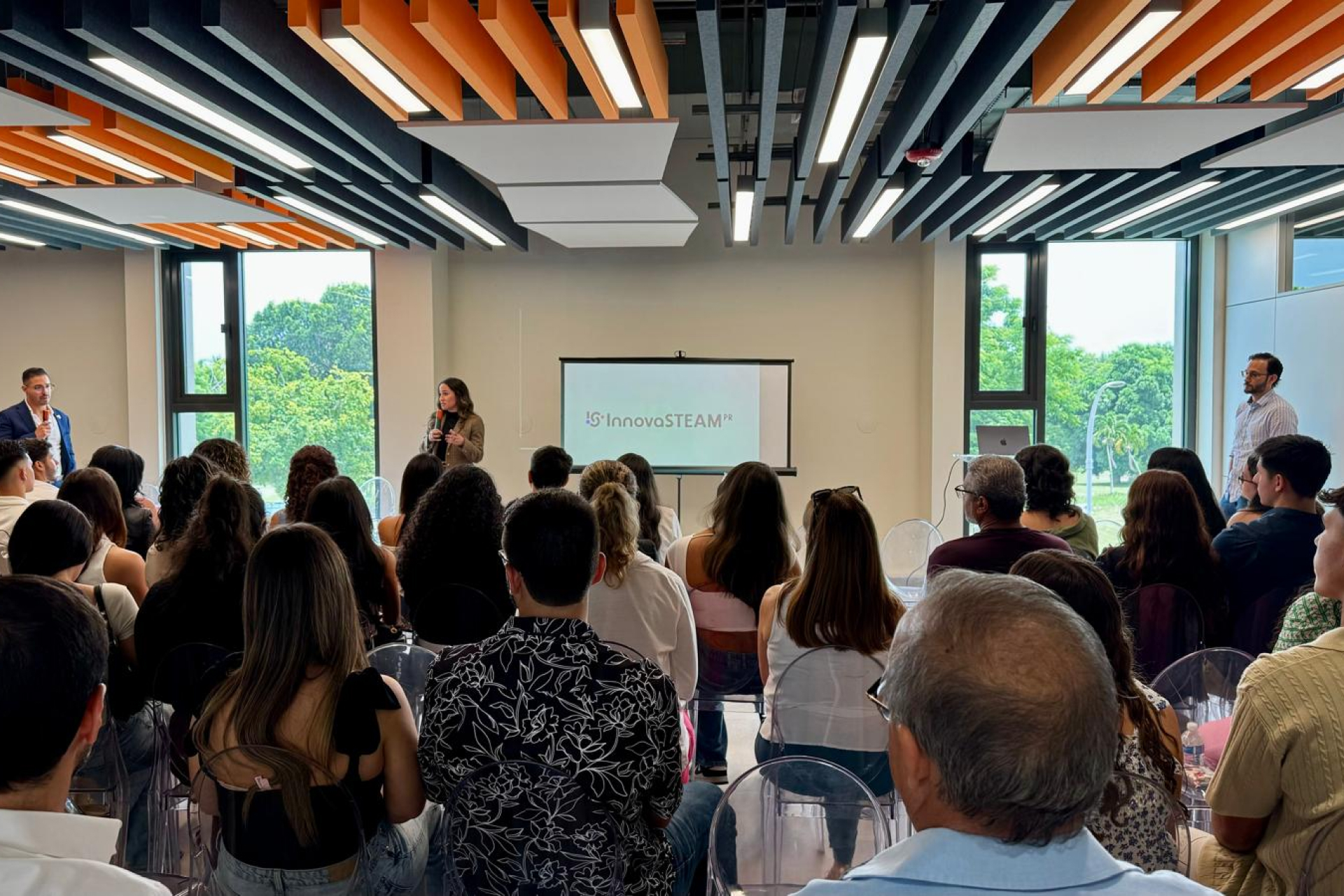 Background picture of InnovaSTEAM PR founders speaking at a panel.