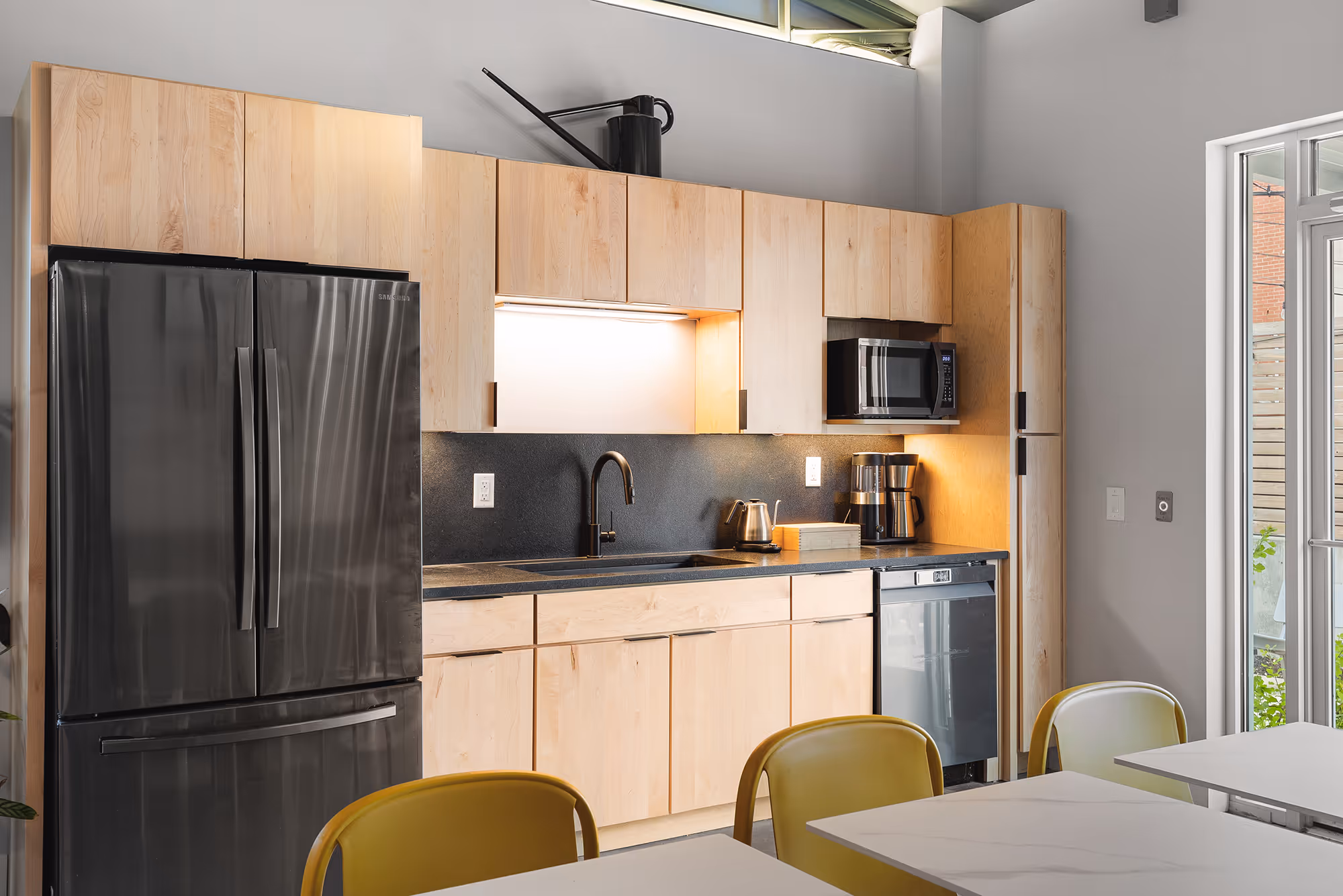 Shared kitchen space at Sideyard with a refrigerator, small appliances, and coffee machine.